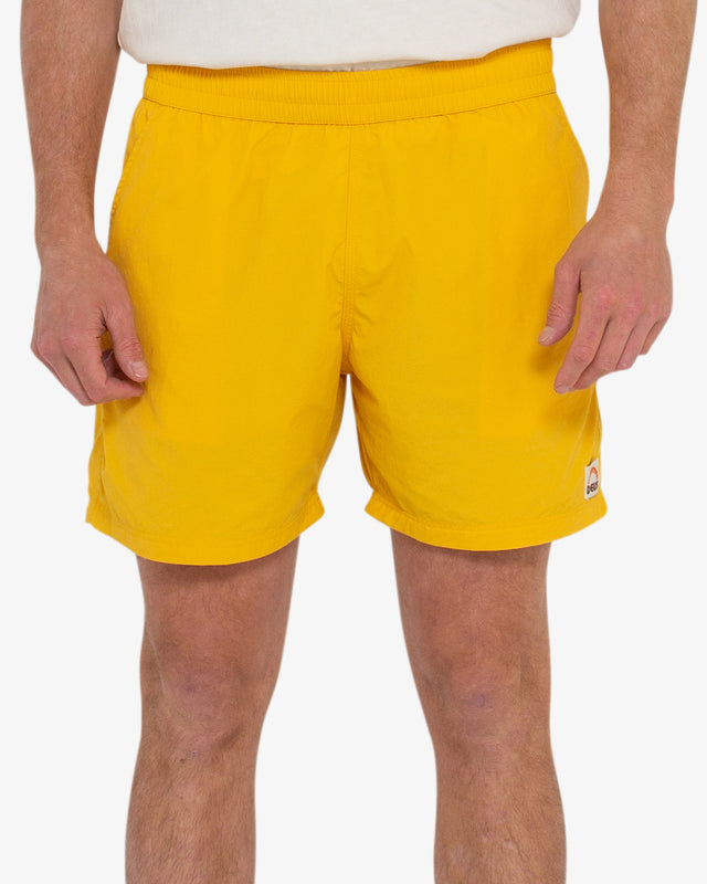 yellow 16 inch leg elasticated waist board short with back flap pocket, contrast stitching, branded woven label, 95% nylon 5% spandex water resistant fabrication with a garment wash